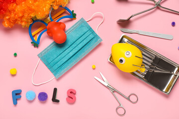 Composition with surgeon's tools and party decor for April Fools Day on pink background