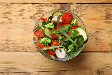 Tasty fresh vegetarian salad on wooden table, top view