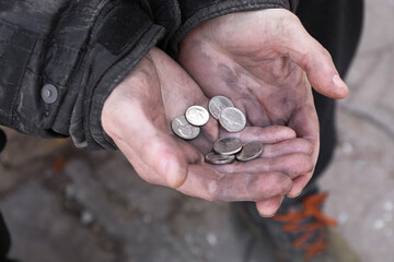 Poor homeless man holding coins outdoors, closeup