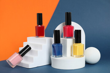 Obraz premium Stylish presentation of bright nail polishes in bottles on color background