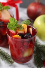 Aromatic Sangria drink in glasses, ingredients and Christmas decor on white marble table