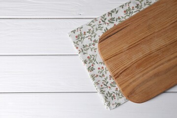 Cutting board and napkin on white wooden table, top view. Space for text
