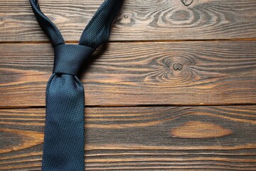 One blue necktie on wooden table, top view. Space for text