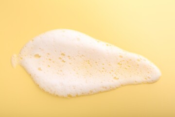 Sample of fluffy foam on yellow background, top view