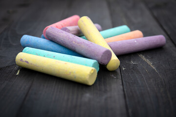 Colorful pieces of chalk on a wooden texture background