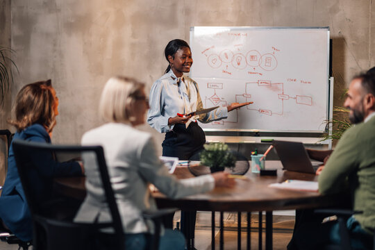 Interracial employee having presentation in front of her team at office