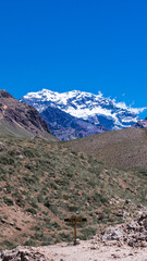Mount Aconcagua dominating the valley, Mendoza, Argentina. Snow covered mountains in winter with a danger sign