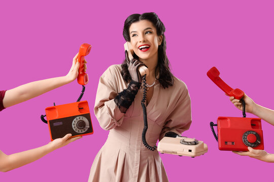Beautiful pin-up woman with vintage telephones on color background