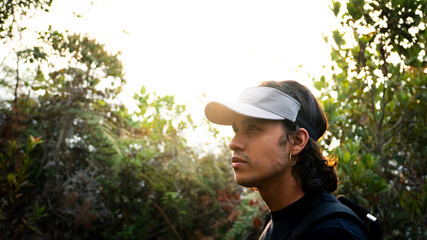 young latin man with long hair and cap in the golden hour