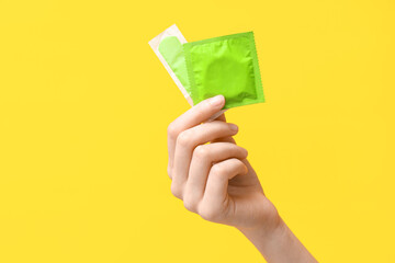 Female hand with different means of contraception on yellow background - obrazy, fototapety, plakaty