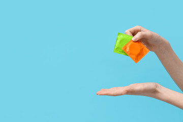 Female hands with condoms on blue background