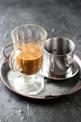 Milk vietnamese coffee in an Irish glass with condensed milk and phin on metal tray - 774413741