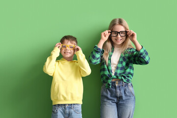 Cute little children in eyeglasses on green background