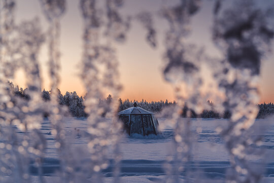 Lever de soleil le matin sur une hutte au milieu d'un lac gel&eacute; en Laponie en Su&egrave;de