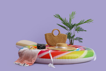 Swimming mattress in shape of candy with camera and bag on lilac background