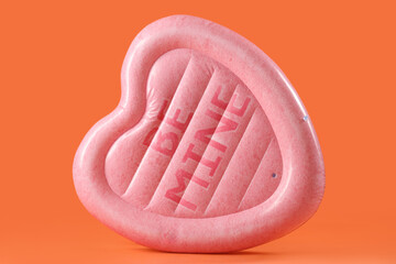 Swimming mattress in shape of heart on orange background