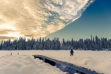 Jeune femme devant une forêt et une étendue de neige au lever du soleil en Laponie en Suède