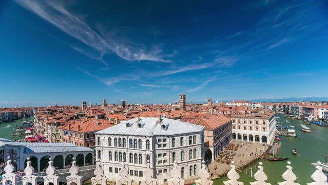 Top panoramic view on central busy canal in Venice timelapse, on both sides masterpieces of Venetian architecture, sailing on gondolas and boats. Blue cloudy sky at summer day over red roofs