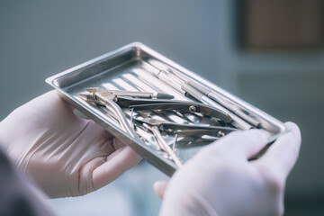 A girl in gloves holds a tray with sterile medical instruments for pedicure - obrazy, fototapety, plakaty