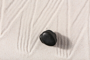 Stack of stones on sand with lines in Japanese rock garden, top view. Zen concept