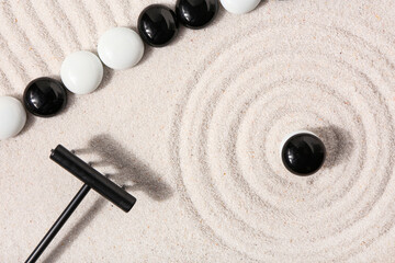 Rake and stones on sand with lines in Japanese rock garden, top view. Zen concept