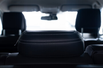 Close-up of rear seat headrest on light blurred background of passenger car interior