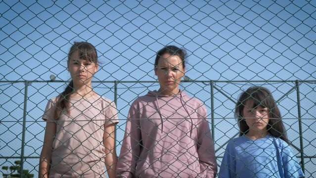 Mother with daughters behind a wire fence.