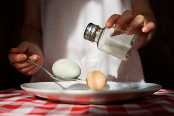 A person is pouring a jar of eggs on a plate with a knife and fork.