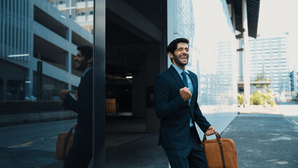 Skilled smart business man dancing with joyful while walking in glass wall. Project manger receive...