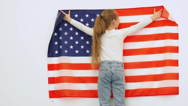 Hang an American flag on the wall. The girl holds the US flag. Independence Day. Flag Day. Education in America. English language learning. American diploma