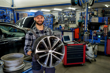 A smiling mechanic, proud owner of a small workshop, stands in his domain, holding a wheel with...