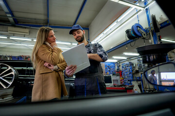 Transparent service: Mechanic uses a tablet to share repair details and costs with a client,...