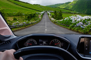 Driver view to the road with beautiful green landscape view from inside a car of driver POV. São Miguel island, Azores, Portugal, Europe.