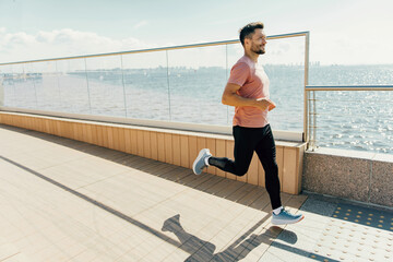 A spirited man jogs along a sunlit promenade by the sea, the joy of exercise evident in his stride...