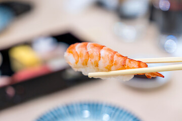 Japanese sushi set. Shrimp sushi on chopsticks.