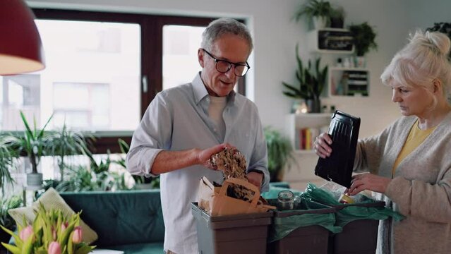 Senior couple sorting garbage in recycling bins at home
