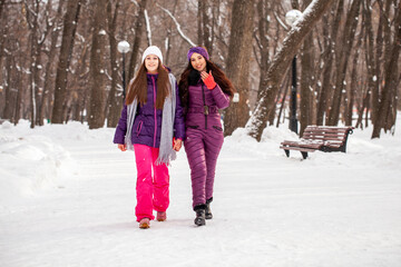 Fototapeta na wymiar Two young happy girlfriends walking in a winter park