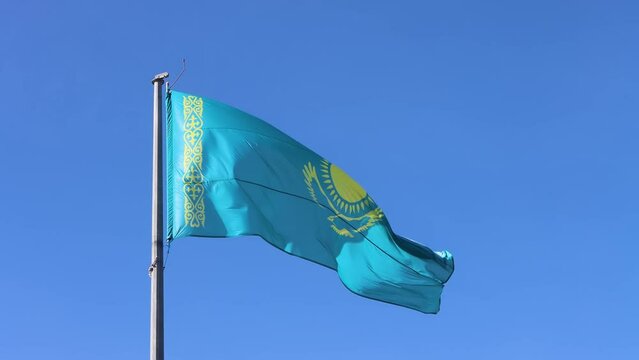 Kazakhstan flag waving on the flagpole on blue sky background. Kazakh symbol on silk flag.