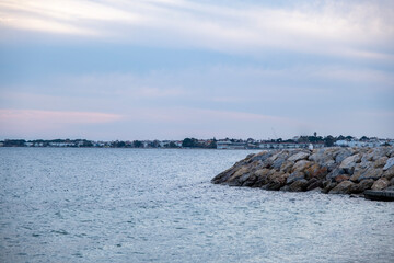 Sunset on the sea with rocks and houses in the background. Yachts and boats on the shore of the sea at sunset