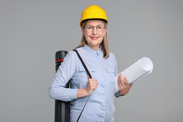Architect in hard hat with draft and tube on grey background