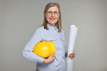 Architect with hard hat and draft on grey background