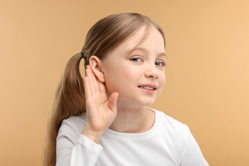 Little girl with hearing problem on pale brown background