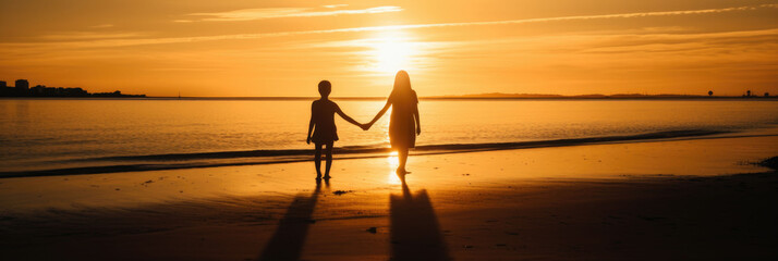 Silhouette of two children holding hands on the beach at sunset, during the golden hour light. National Siblings day. banner