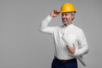 Architect in hard hat holding draft on grey background. Space for text