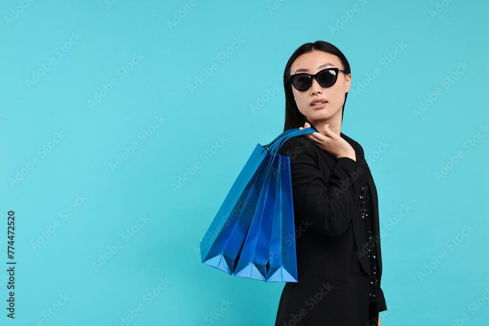 Sticker Beautiful woman with shopping bags on light blue background. Space for text