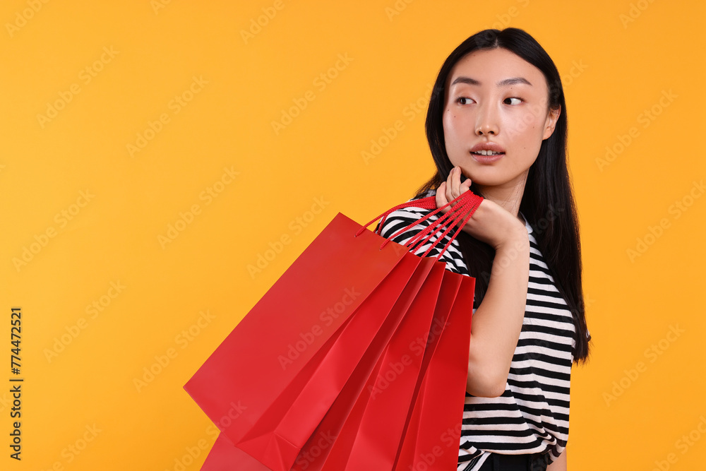 Wall mural Beautiful woman with shopping bags on yellow background. Space for text