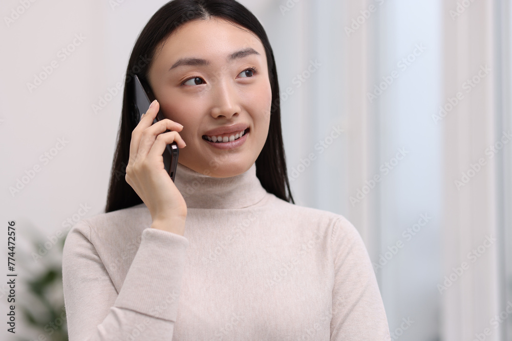 Wall mural Portrait of smiling businesswoman talking on smartphone in office