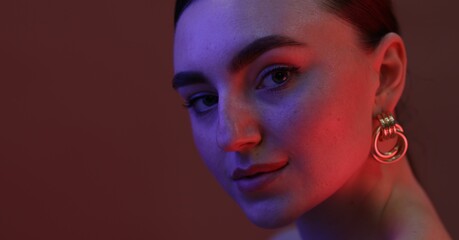 Portrait of beautiful young woman on color background in neon lights, closeup. Space for text