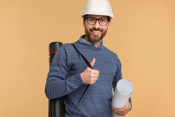 Architect in hard hat with drawing tube and draft on beige background