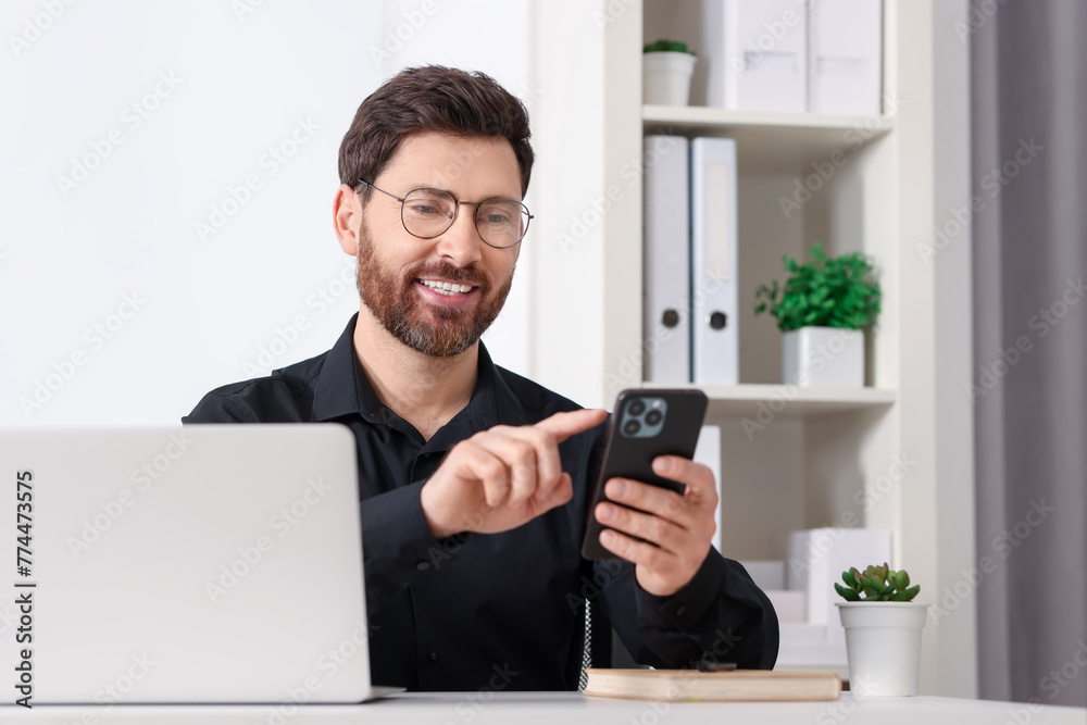 Canvas Prints Smiling man in shirt using smartphone in office